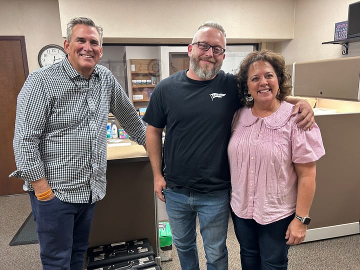 Donald Noordhof stands at a desk with Jonathan Rocke and Martha Steffen in the Pathway Ministries offices.