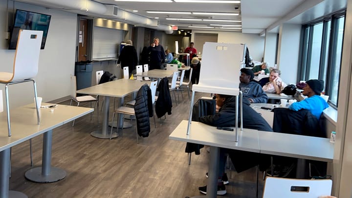 A long hallway featuring several tables and chairs arranged along its length, creating a spacious and inviting atmosphere.